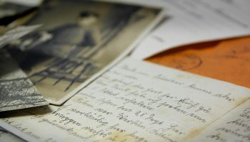 Old handwritten letters and vintage photographs spread on a table, creating a nostalgic feel.